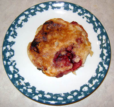 closeup of a strawberry pancake with a large strawberry piece showing through!