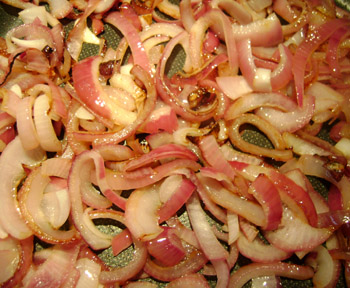 sauteed red onion slices in a frying pan
