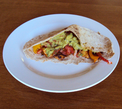 Chicken Fajitas in a Whole Wheat Pita Pocket filled with juicy chicken, bell peppers, and creamy avocado, served on a white plate.