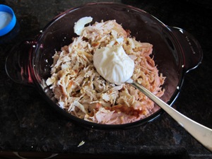 adding a spoon of mayo to the chicken salad