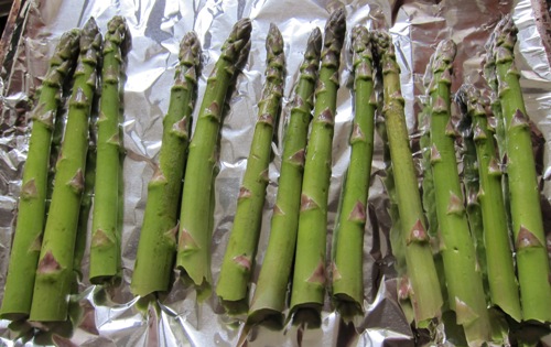 raw asparagus lined up on a baking sheet