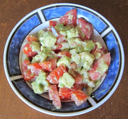 a bowl of salad with tomatoes, avocado and onion
