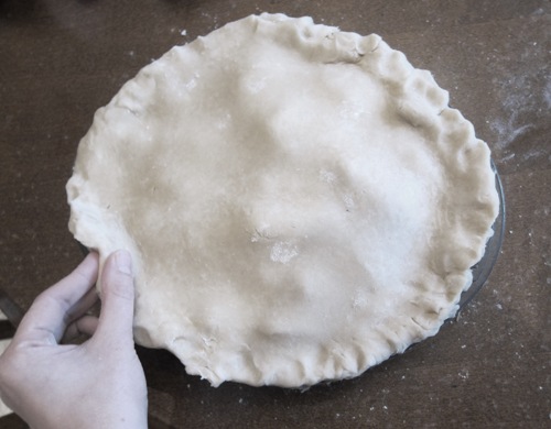 pinching the edges of the apple pie to seal