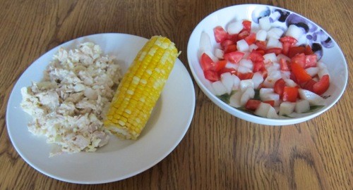 chicken salad, corn on the cob and cucumber salad