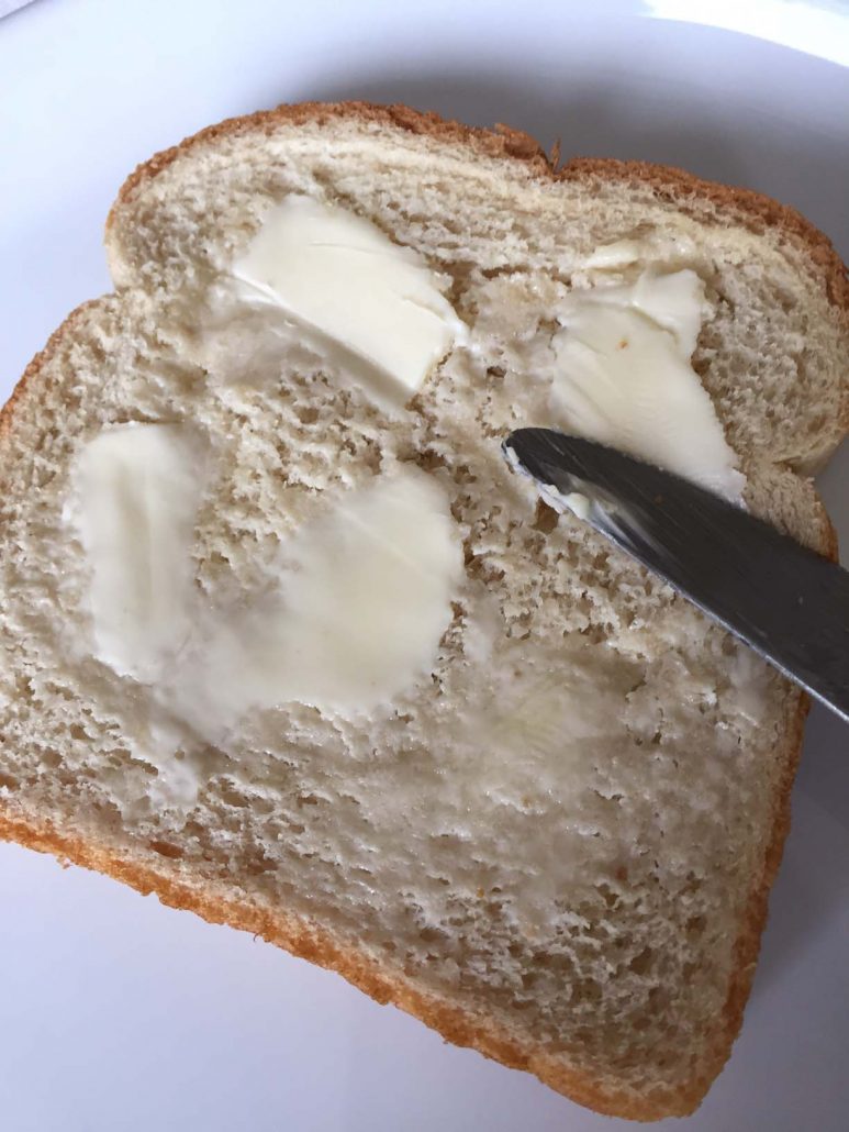 Spreading butter on slice of bread