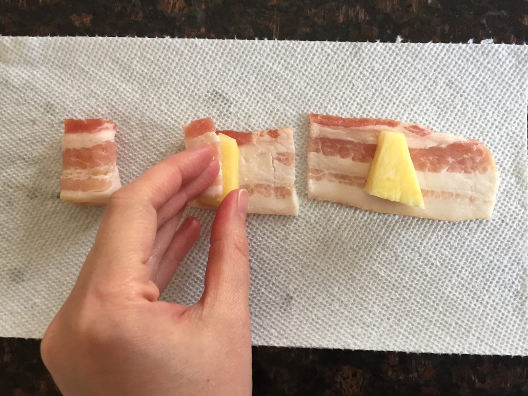 Wrapping pineapple chunk with bacon