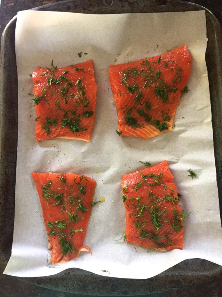 salmon fillets with dill on baking sheet