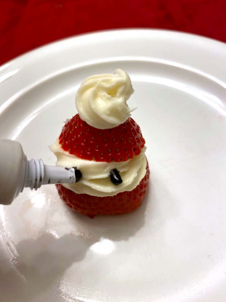 strawberry santa drawing eyes with icing gel pen
