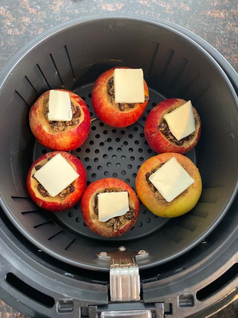 Stuffed apples topped with butter ready to bake in the air fryer basket