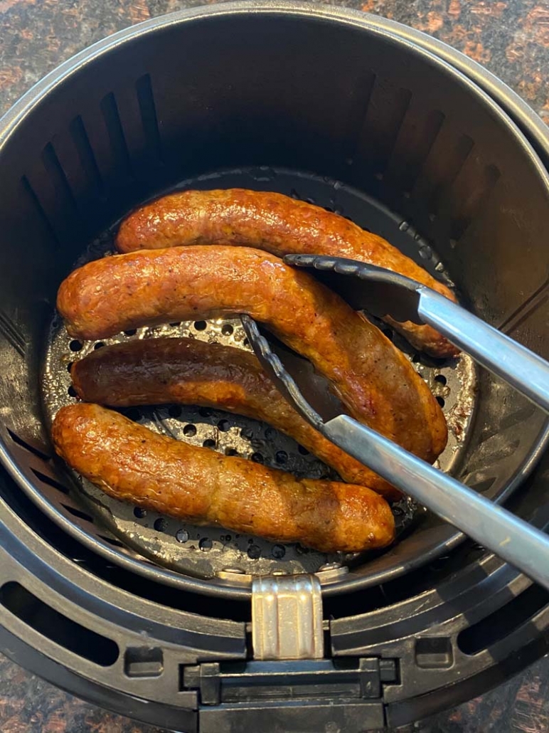 removing sausages from air fryer basket with tongs