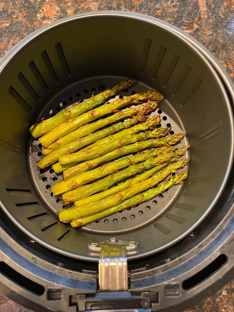 Asparagus stalks roasted at the bottom of an air fryer