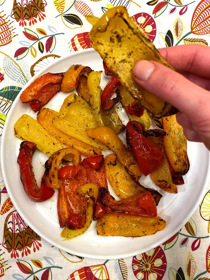 Woman holding a yellow bell pepper with a charred edge that was roasted in an air fryer.