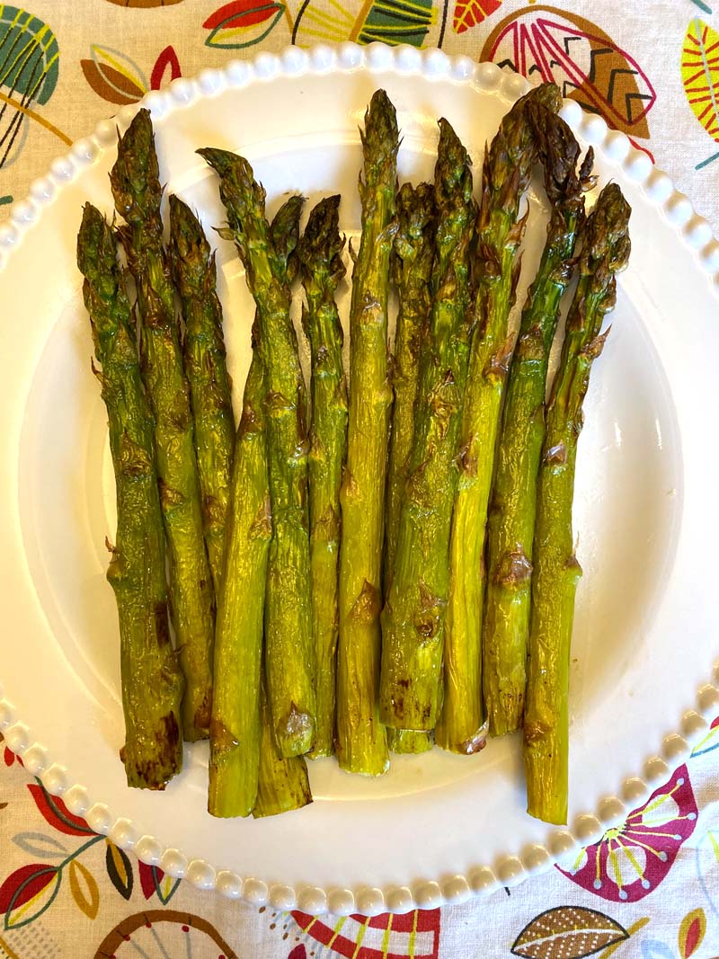 Perfectly roasted air fryer asparagus on a white plate.