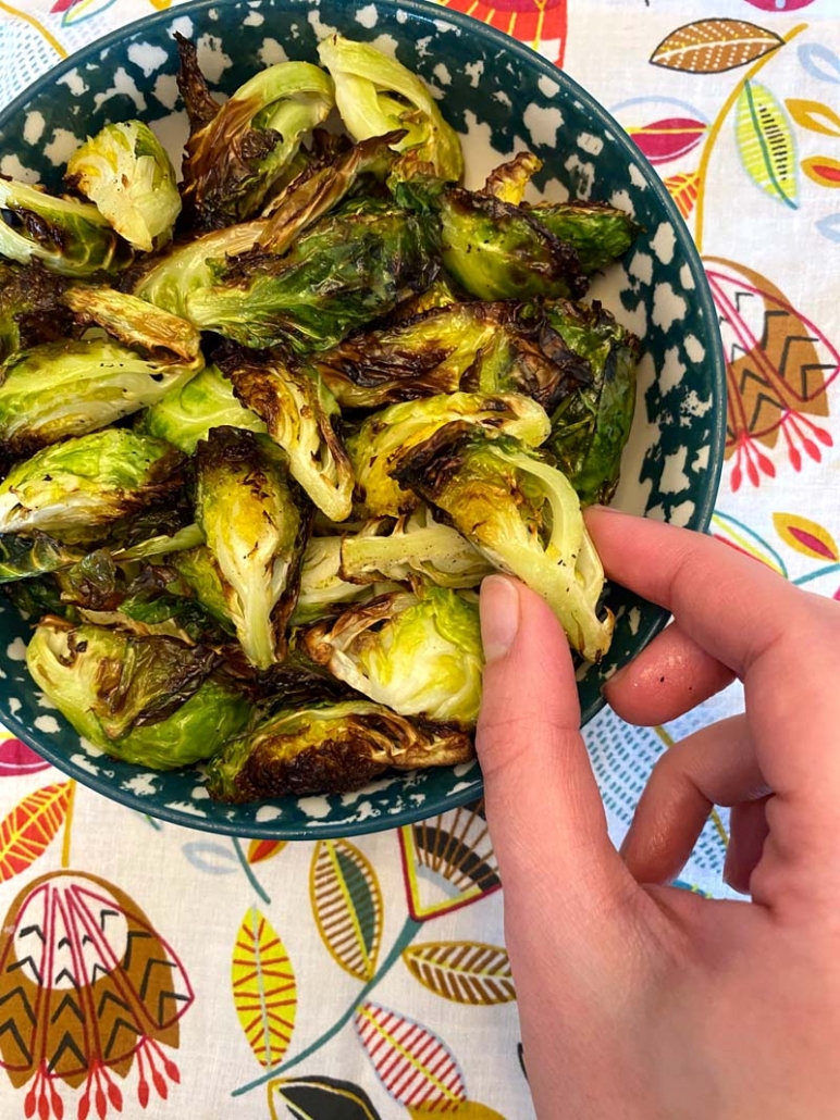 Eating Air Fryer Brussels Sprouts in a blue and white bowl