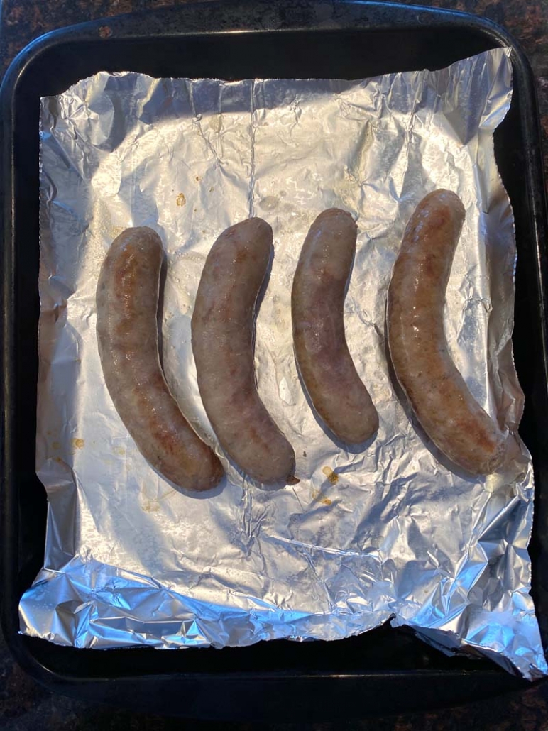 boiled sausages roasting on a foiled sheet pan