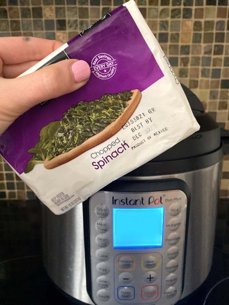Woman holding a bag of chopped frozen spinach in front of an instant pot