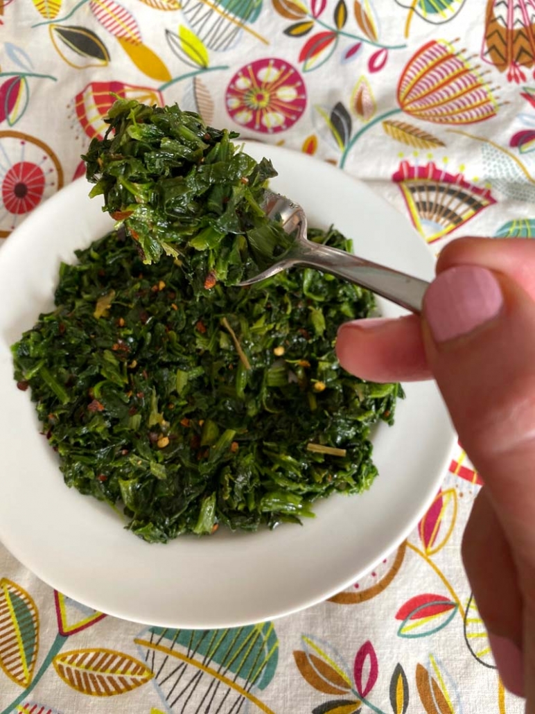 Fork filled with chopped spinach and red pepper flakes.
