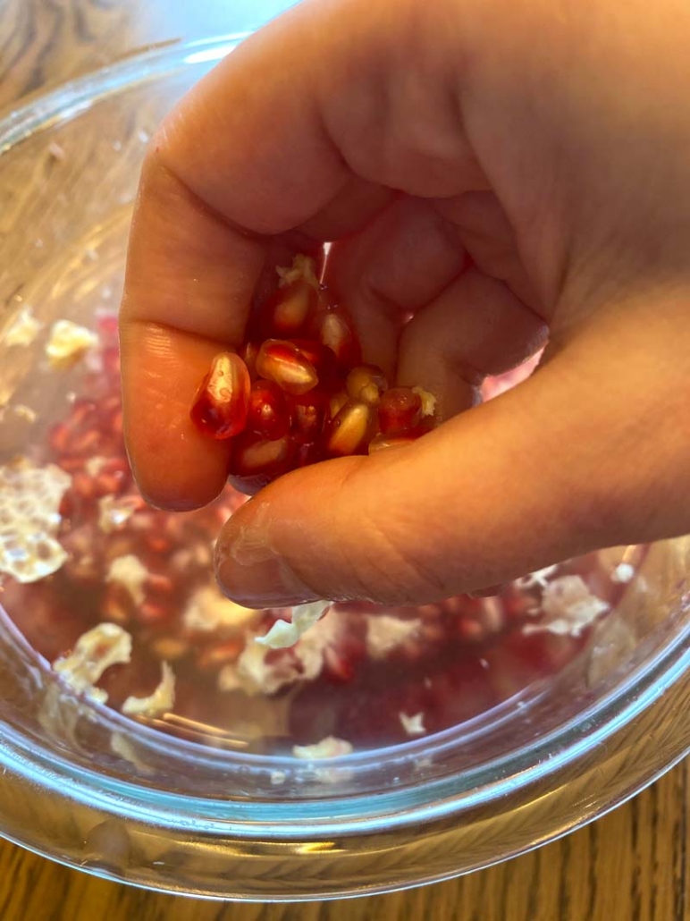 Woman showing how to cut a pomegranate properly using a bowl of water