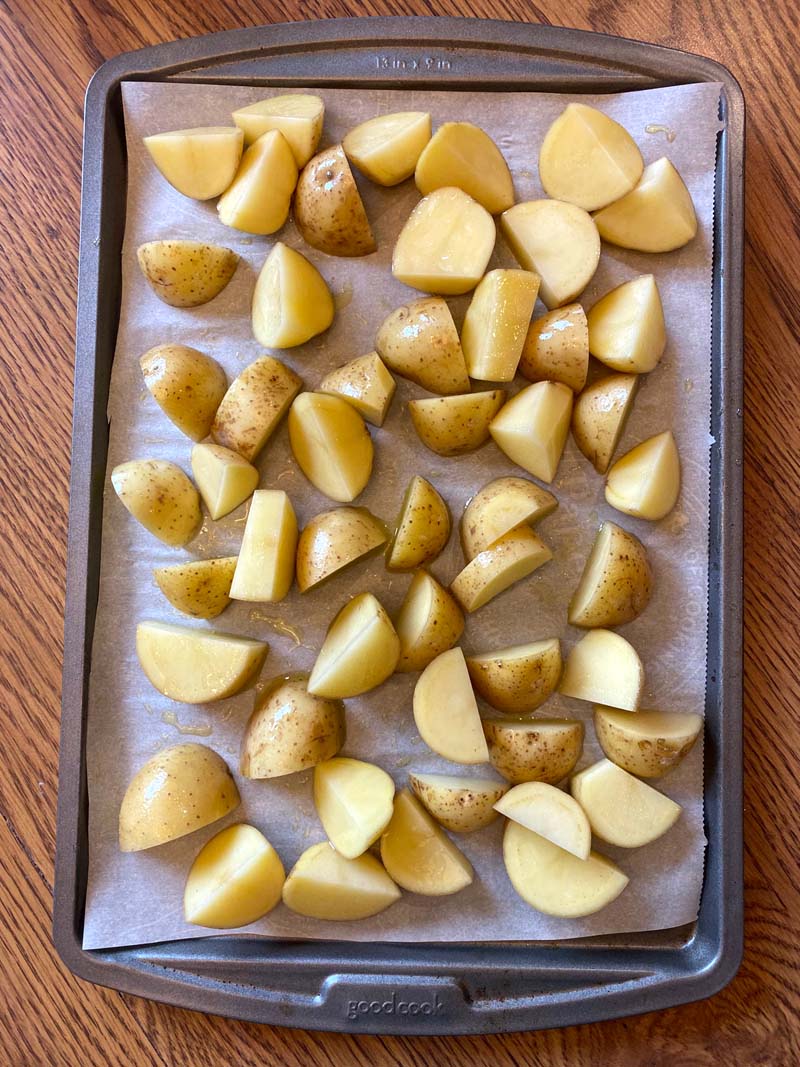 quartered potatoes on a baking sheet covered with parchment paper