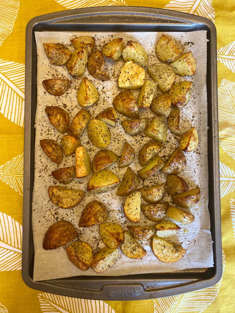 Baking sheet with roasted potatoes sprinkled with pepper