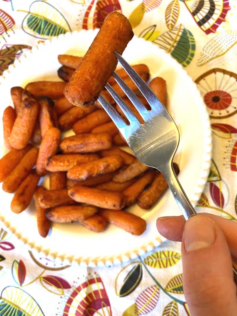 holding a baby carrot with a fork