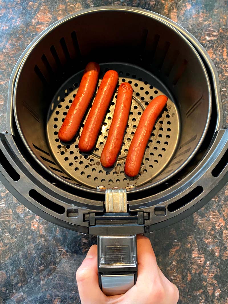 Four hot dos sausages in an air fryer basket