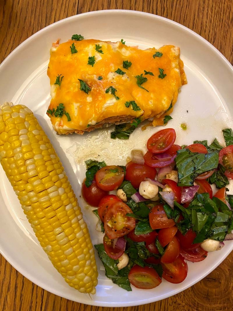 salmon dinner with corn on a cob and tomato salad