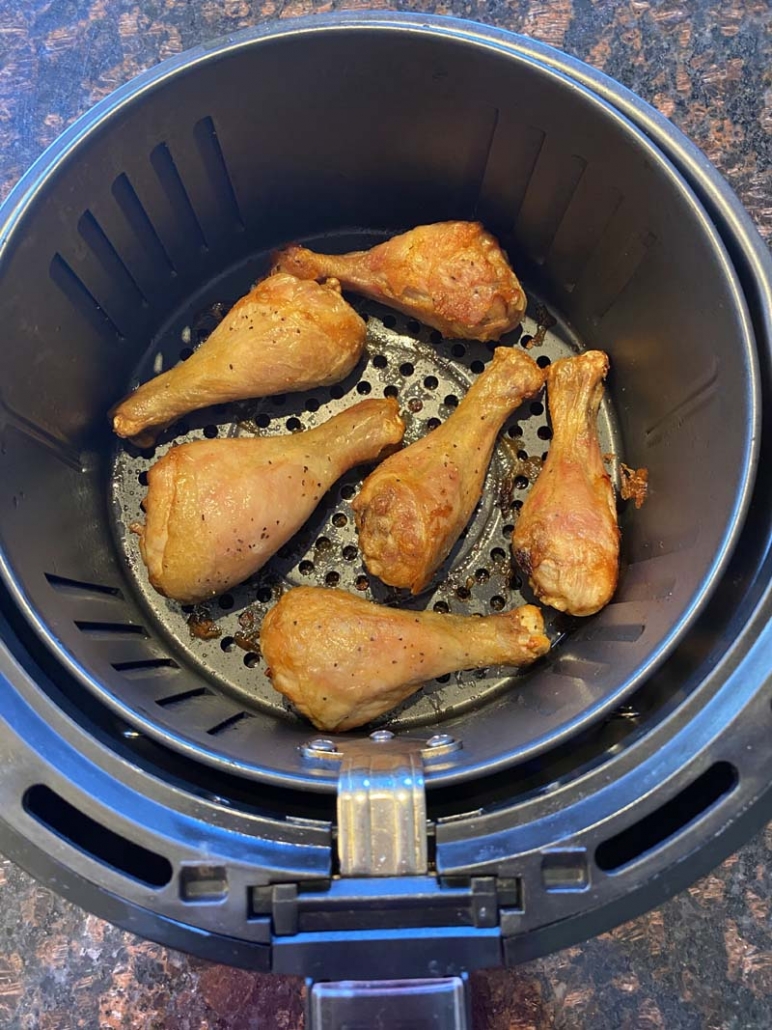 Cooked chicken drumsticks in an air fryer basket 