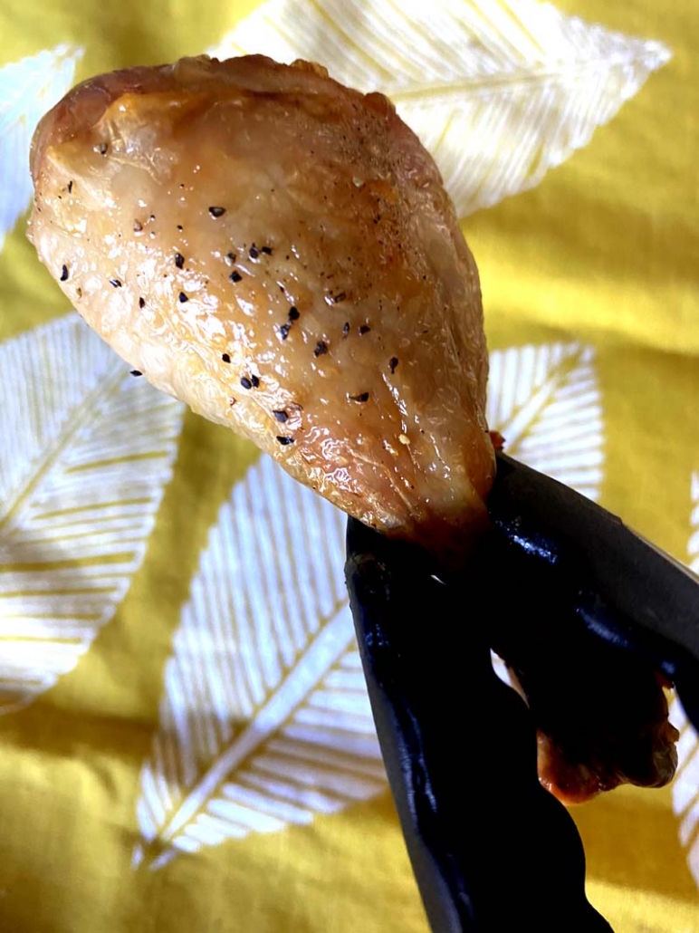 roasted chicken leg held with tongs