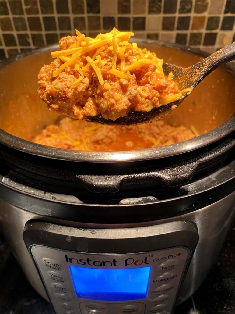 a black ladle full of keto chili cooked in an instant pot