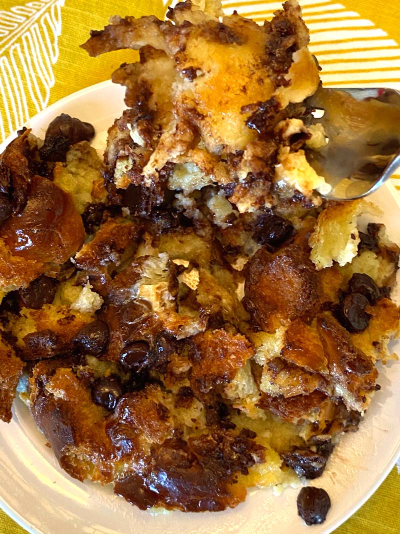 Bread pudding served on a white plate with a spoon