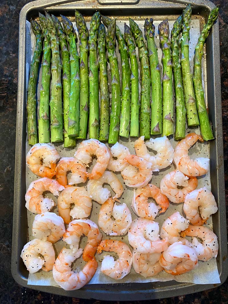 Shrimp and asparagus on a baking sheet before being cooked