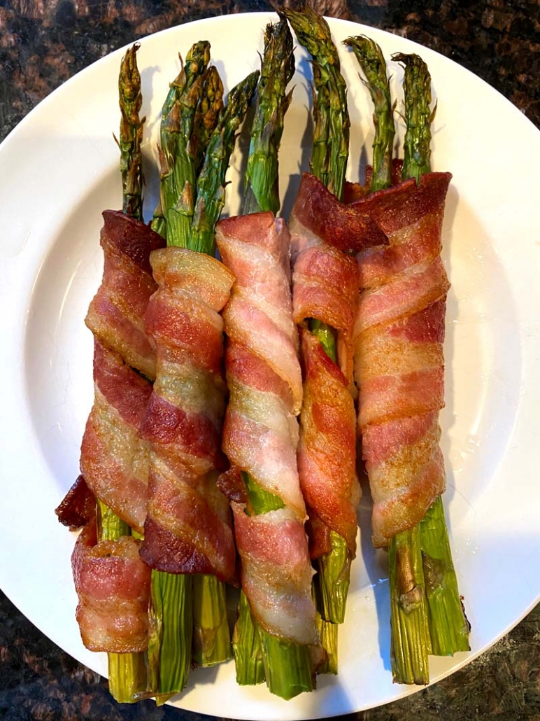bacon wrapped asparagus on a white plate