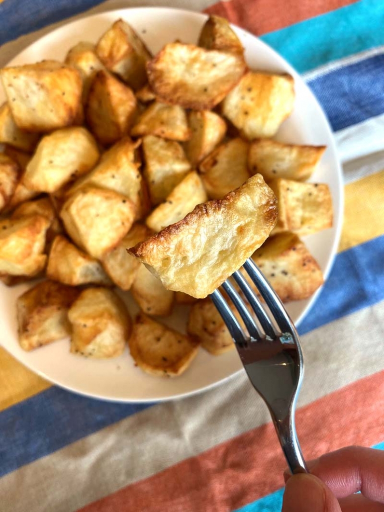 The roasted potatoes on a plate with a fork