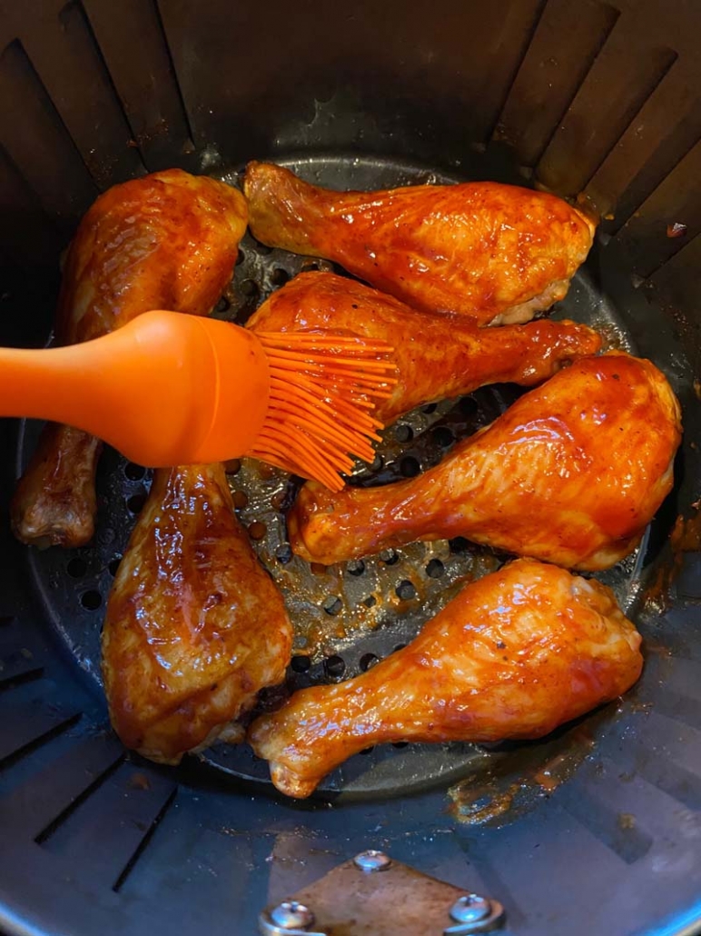 brushing chicken legs with bbq sauce
