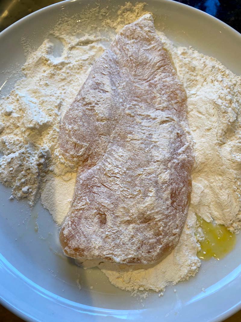 Chicken breast being covered with flour