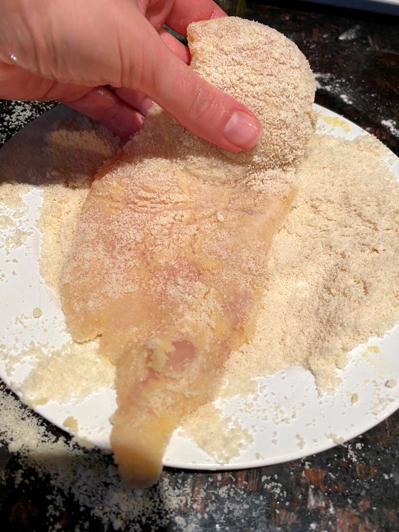 Chicken breast being dipped in almond flour