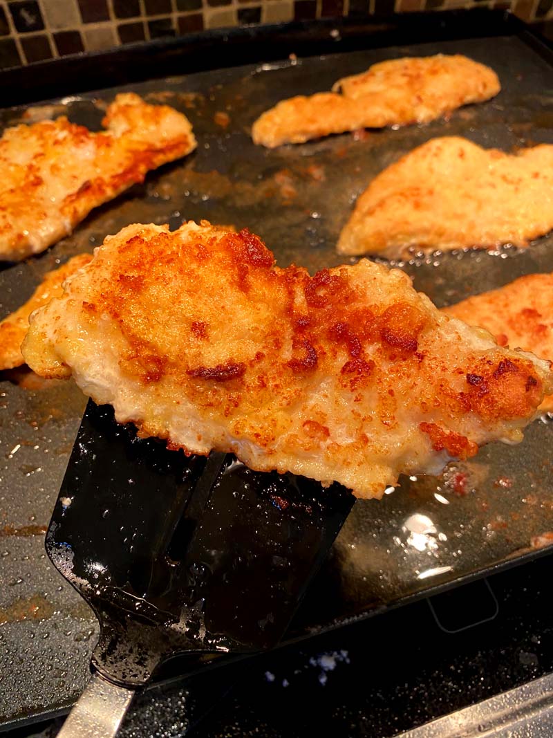 A piece of the fried chicken being turned over with a spatula