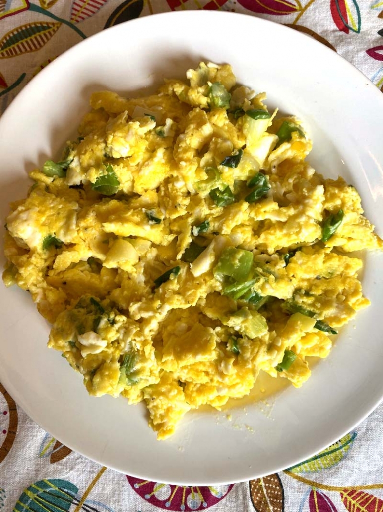 scrambled eggs with green onions on a white plate 