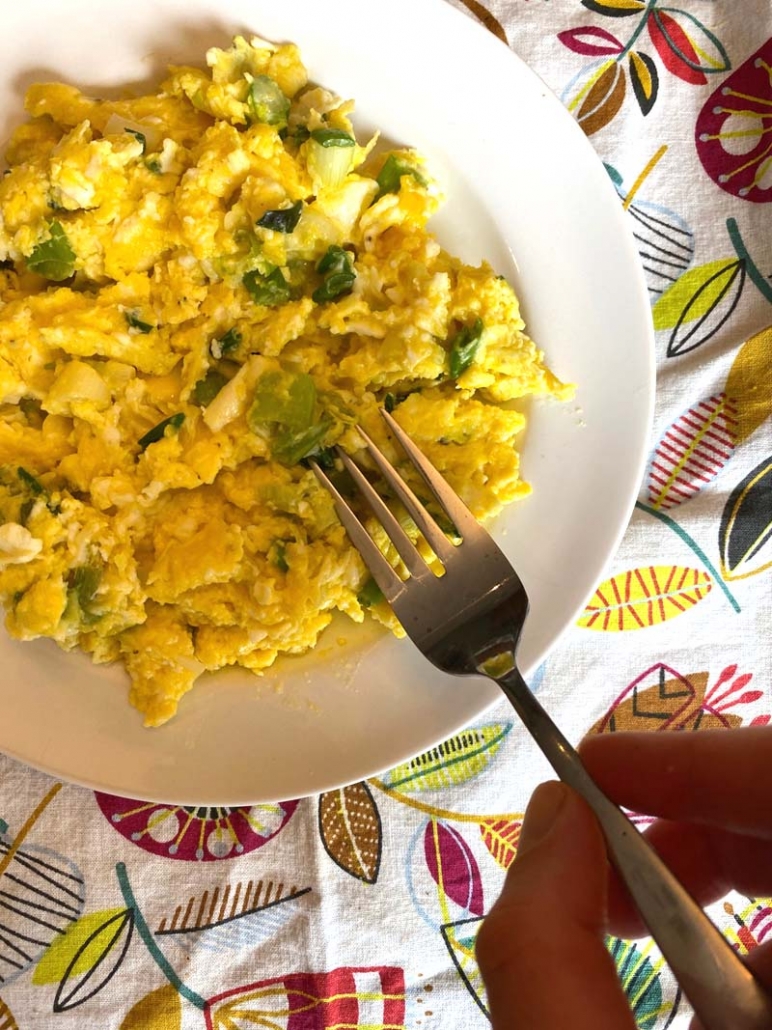 eating green onion scrambled eggs with a fork 