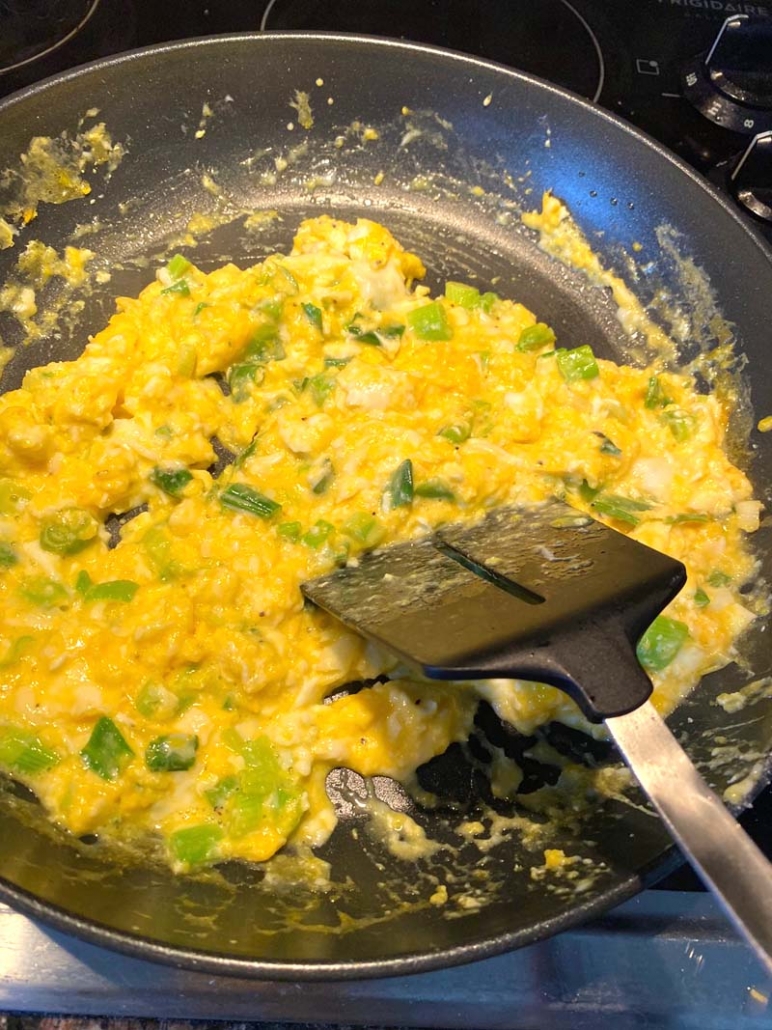 cooking scrambled eggs in a black pan 