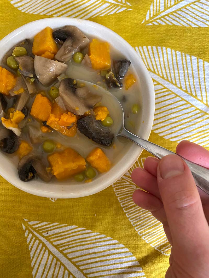 Easting the mushroom sweet potato soup with a spoon
