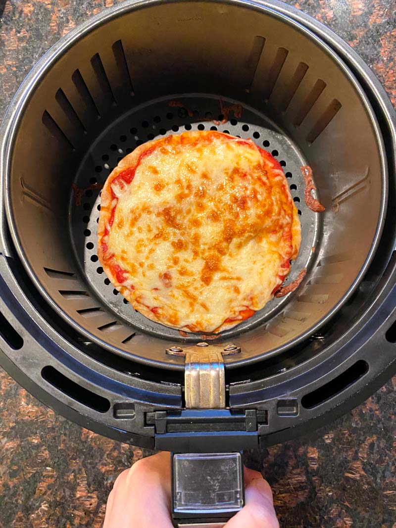 The cooked pita pizza in the air fryer basket
