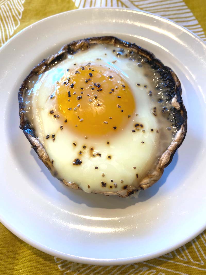 A portobello with baked egg on a white plate