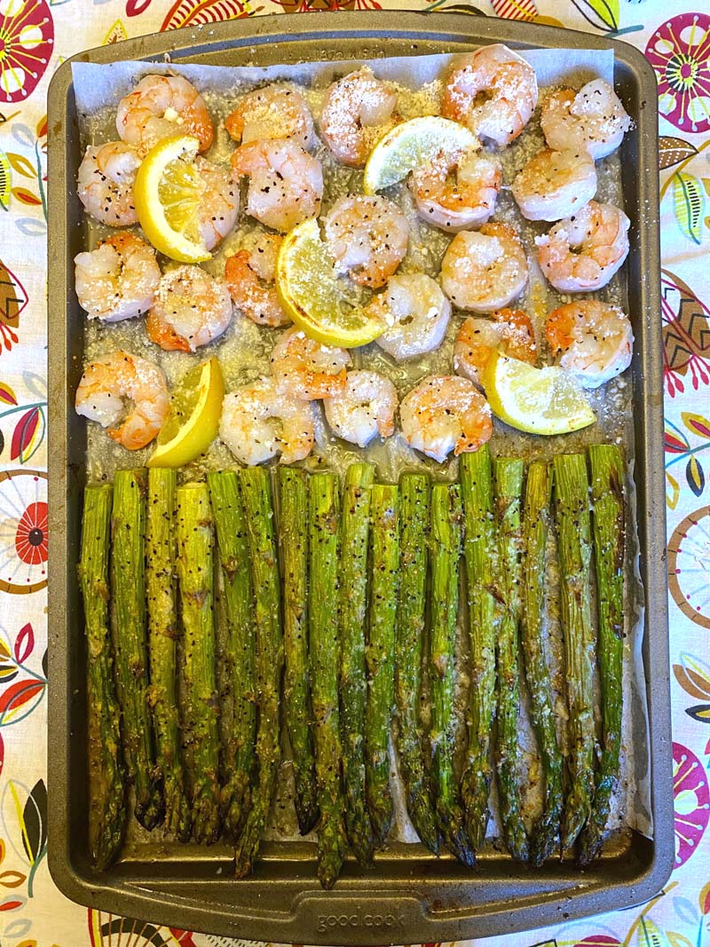 Shrimp and asparagus on two halves of a sheet pan