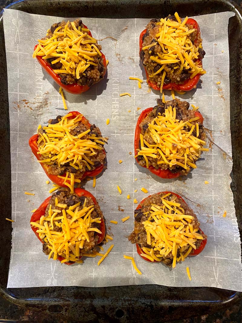 six stuffed bell peppers topped with cheese before baking