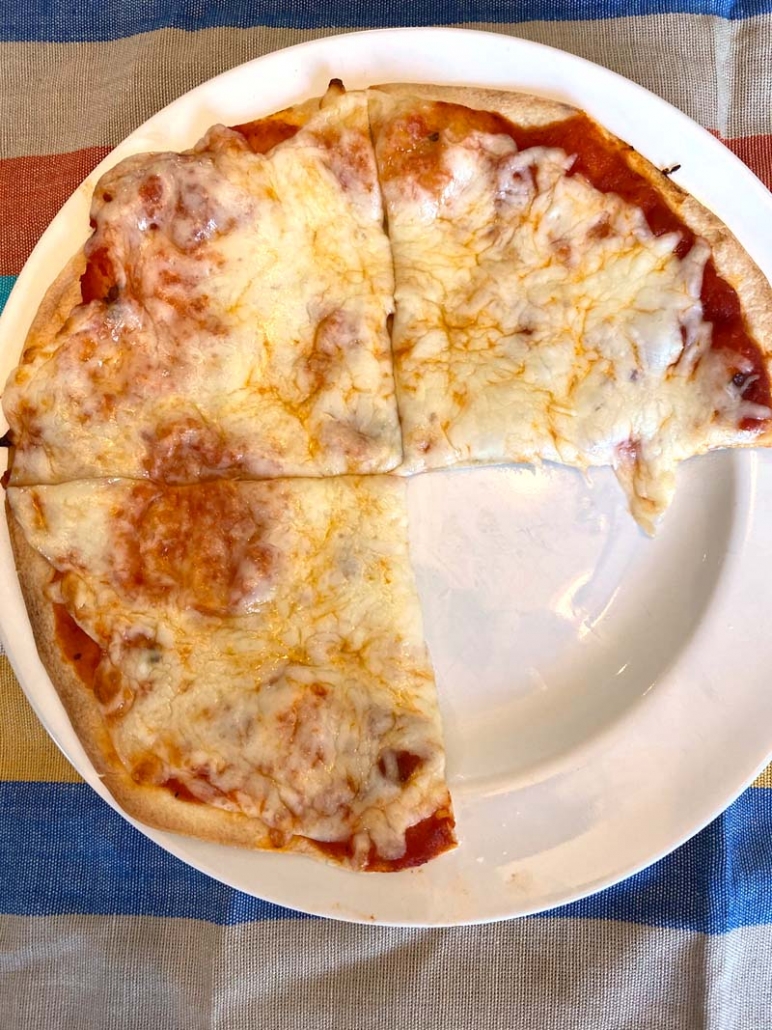 tortilla pizza on a white plate with one slice eaten