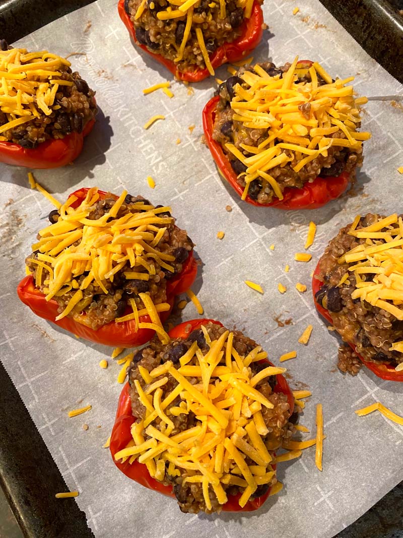Stuffed peppers topped with cheese on a baking sheet
