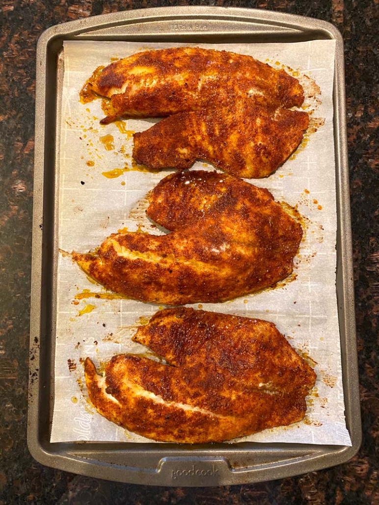 seasoned tilapia fillets on a sheet pan