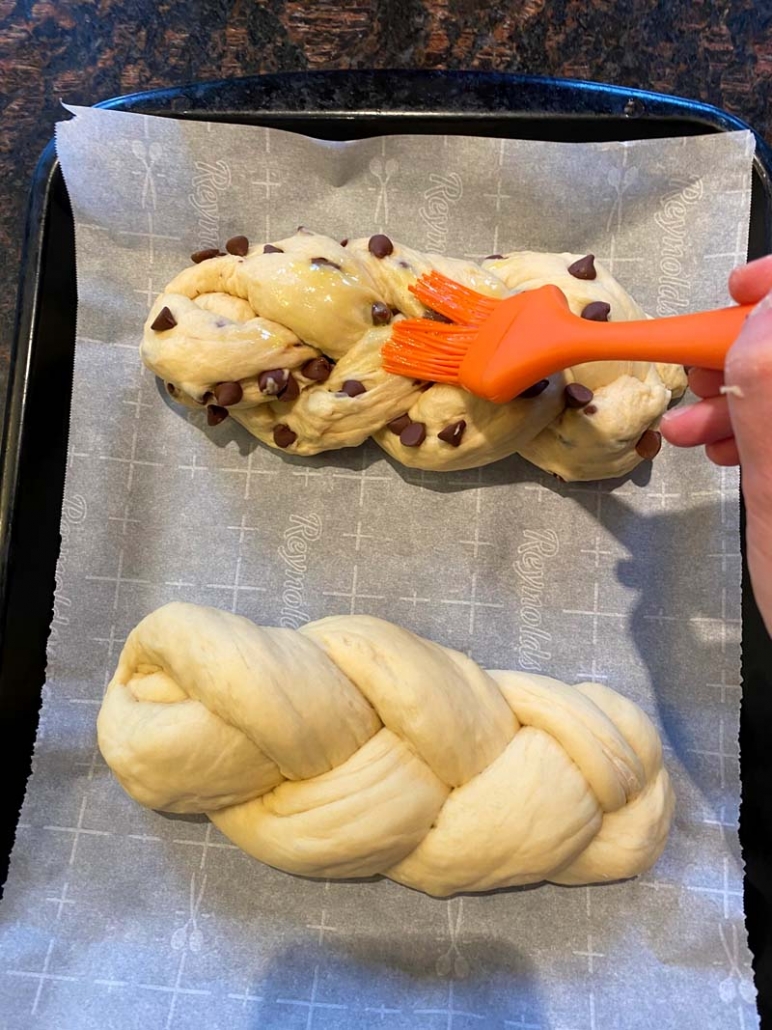 adding egg wash to challah bread recipe with pastry brush